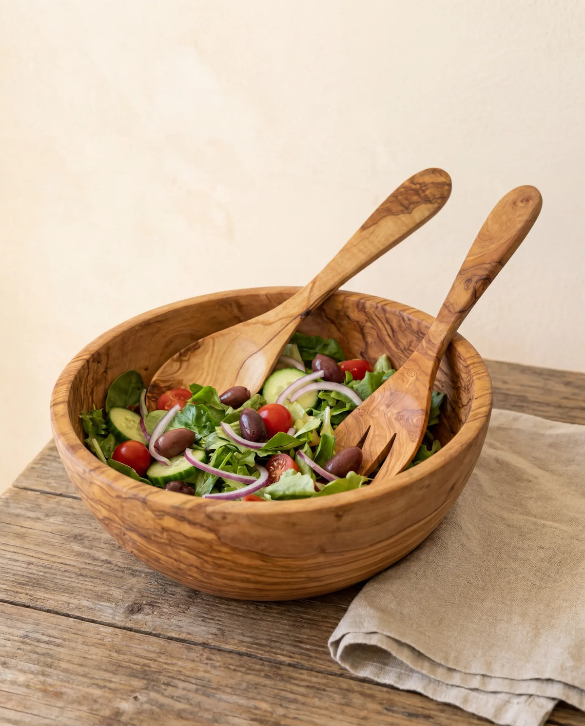 Olivenholz-Salatbesteck in einer Schüssel mit frischem mediterranem Salat